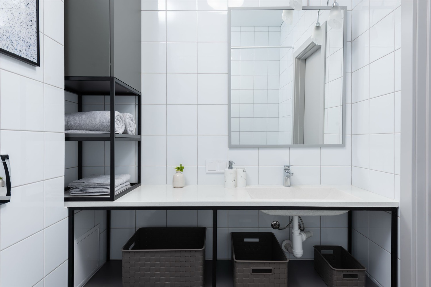 A tiled bathroom with a basin, mirror and open shelving