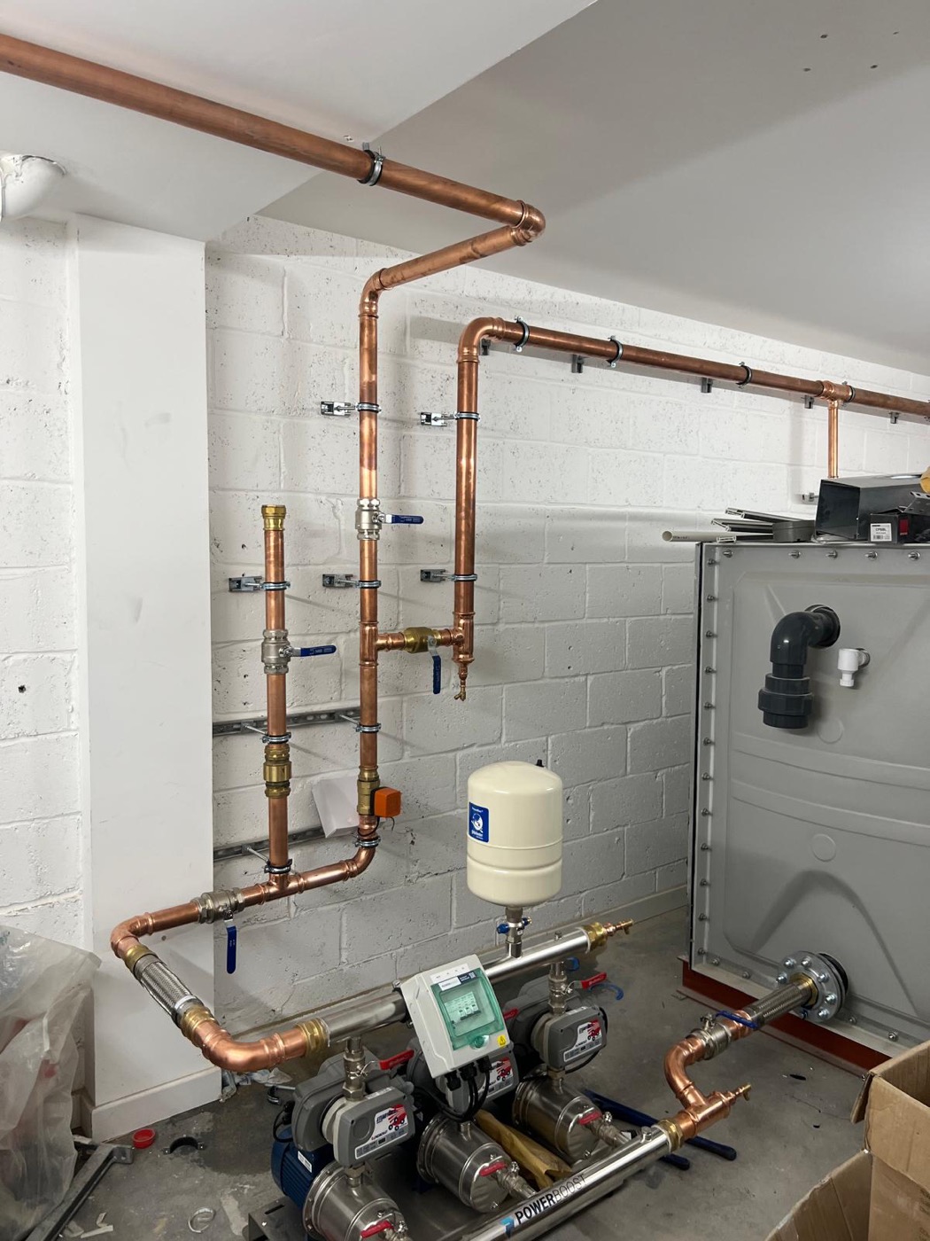 A booster pump set and cold water storage tank with new copper mains pipework — the fix for a property where pressure upstairs was never right.